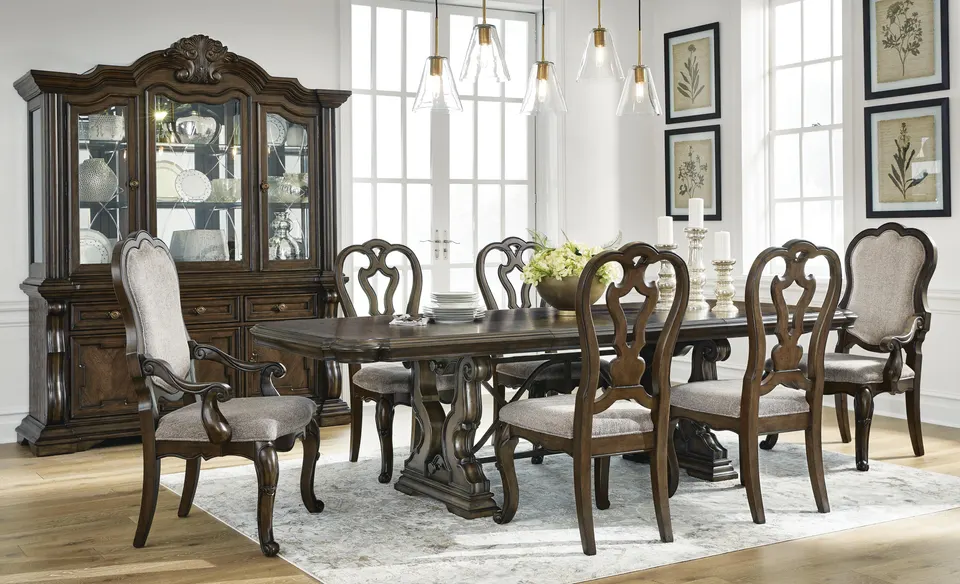 Carved dining table and chairs with a matching china cabinet under glass pendants
